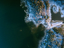 aerial view over a snowy highway along a shoreline 