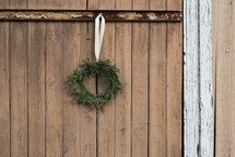 An evergreen wreath hanging on a wooden gate.