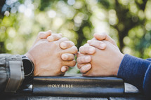 Hands folded on Bible in prayer