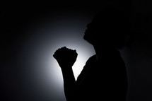 Silhouette of an Asian woman praying