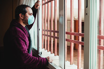man looking out a window longingly 