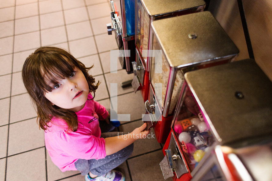 a child getting a toy out of a vending machine 