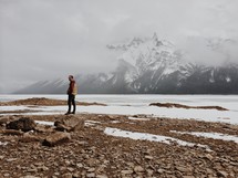 man standing in front of a snow covered mountain 