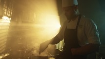 Expert chef using ladle in a pot with sunset light on the background