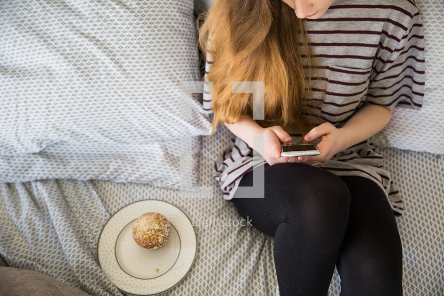 girl texting sitting on her bed 