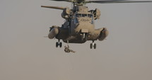 Soldier repelling to the ground from a military transport helicopter during an army rescue operation.
