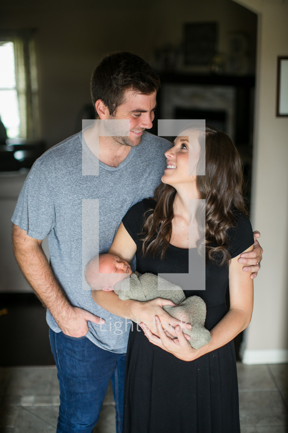 mother and father holding a swaddled newborn 