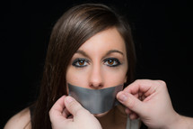 A woman whose mouth is duct taped
