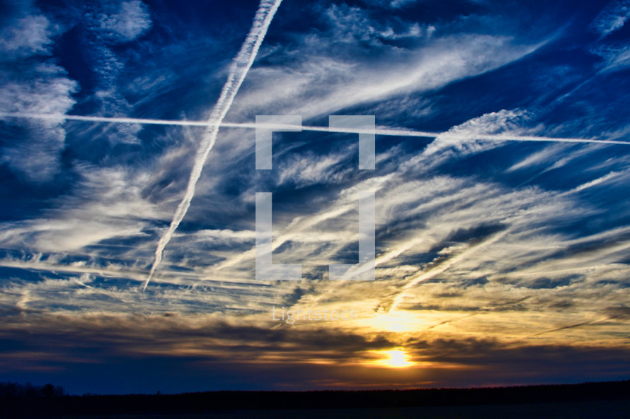plane contrails in the sky at sunset 