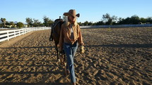 A senior cowgirl walking with her horse