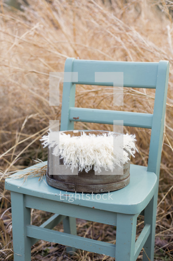 basket in a blue chair in hay 