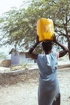 A woman in Haiti carrying a water jug on her head