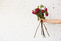 a woman holding a bouquet of dying roses