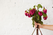 a woman holding a bouquet of dying roses 