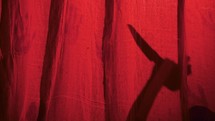 Killer With Knife Behind Red Curtain