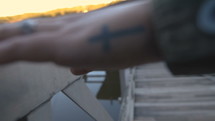 a woman with a cross tattoo on her hand touching a railing 