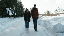 Two lovers walking in the snowy road 