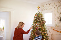 a mother and her young son decorating a Christmas tree