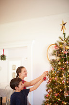 children decorating a Christmas tree together