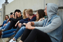group of teens sitting on a parking deck 