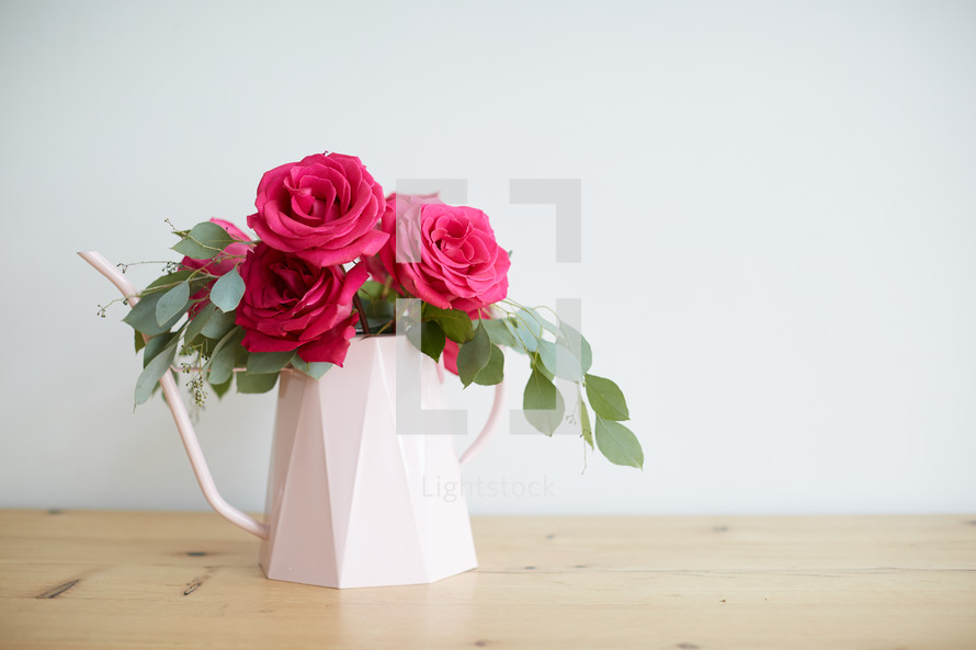 a floral arrangment in a watering can 