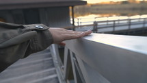 a woman rubbing her hand across a railing on a dock 