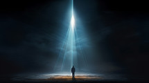 Man standing looking at a beam of light from a dark sky. 