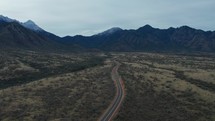 Aerial of a country road heading towards dramatic mountains