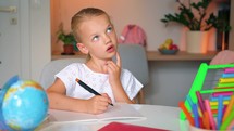 Serious Girl kid primary class student write exercise homework home learning education. Distance learning school. child at home in a lesson virtual. 