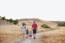 family walking on a dirt road holding hands 