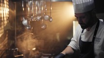 Steam vapor and lights surrounding the work of a chef 