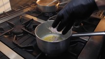 Putting sliced onion inside a pot with oil 