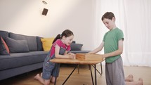 Boy and girl playing a wooden table game at the living room together