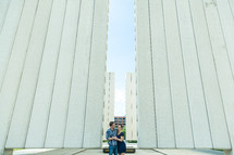 a couple embracing standing outdoors between buildings 