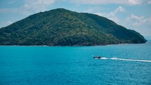 Small boat drives on crystal clear blue water to exotic island. Boat trip. Long Tail Boat. 