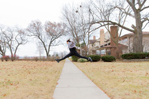 a girl leaping over a sidewalk 