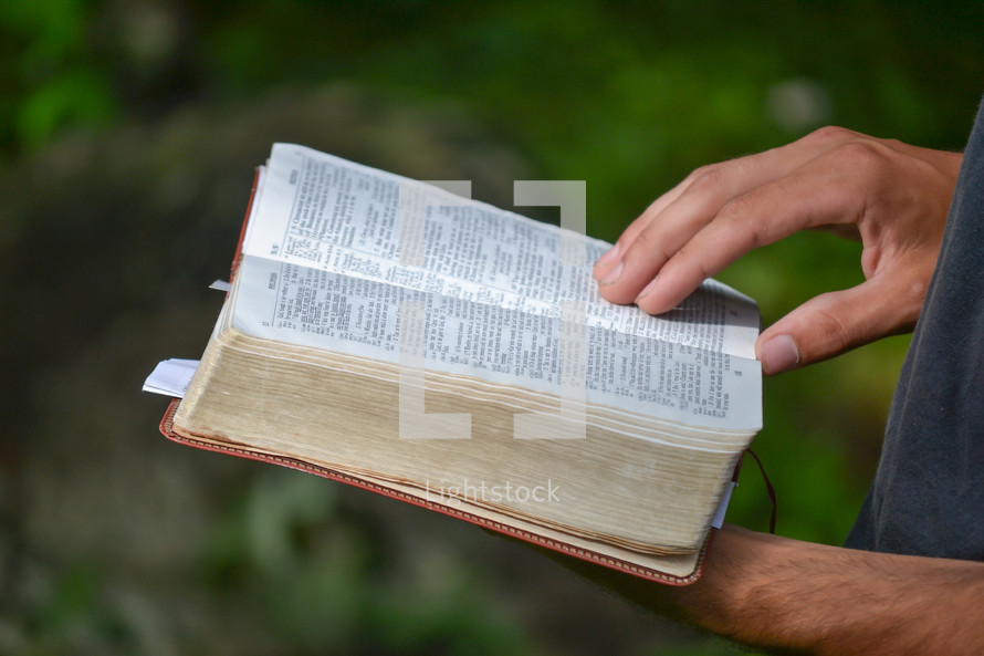 a person reading a Bible outdoors 