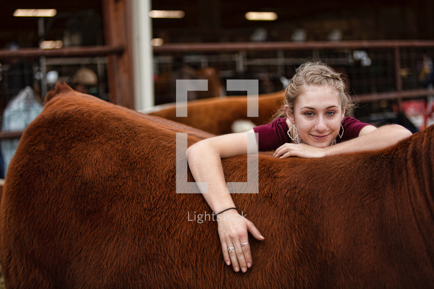 Country girl relaxes contentedly while she leans on the heifer she raised from a calf. 