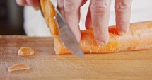 Slow motion close up of a chef knife slicing a carrot