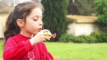 cute little girl blowing soap bubbles in slow motion