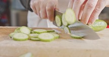Slow motion close up of a chef knife slicing a cucumber