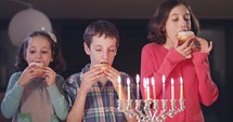 Kids eating donuts with a menorah.