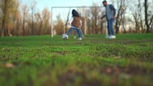 Little boy playing football with parents in the sunny park. Joyful parents and son. Slow motion of happy family playing outdoor in the nature.