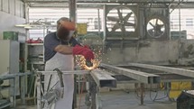 Slow motion of a worker using metal grinder with sparks flying at a metal shop