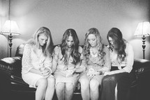 women's group holding hands in prayer on a couch 