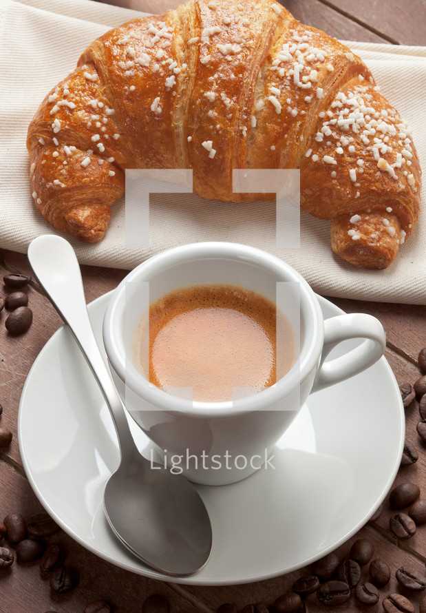 Espresso with croissant in the tray of brown wood
