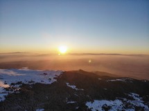 sun rising above snowy mountaintops 