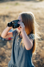 a girl child looking through binoculars 
