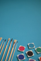 paints and paint brushes on a blue background 