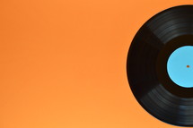 half old black vinyl record with blank cyan label on orange background